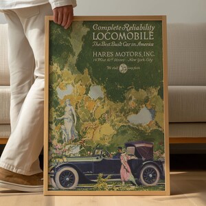 May include: A framed vintage advertisement for the Locomobile, featuring a classic car and figures in a garden setting. The text reads "Complete Reliability LOCOMOBILE" and "HARE'S MOTORS, INC."