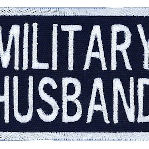 May include: White embroidered patch on a dark blue background with the text "MILITARY HUSBAND".