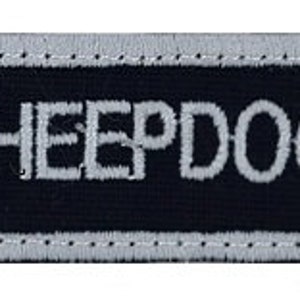 May include: A black and white embroidered patch with the text "SHEEPDOG" in white lettering and two stylized wolf heads on either side of the text.