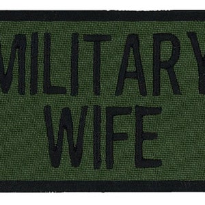 May include: A green military patch with black stitching that reads "MILITARY WIFE".