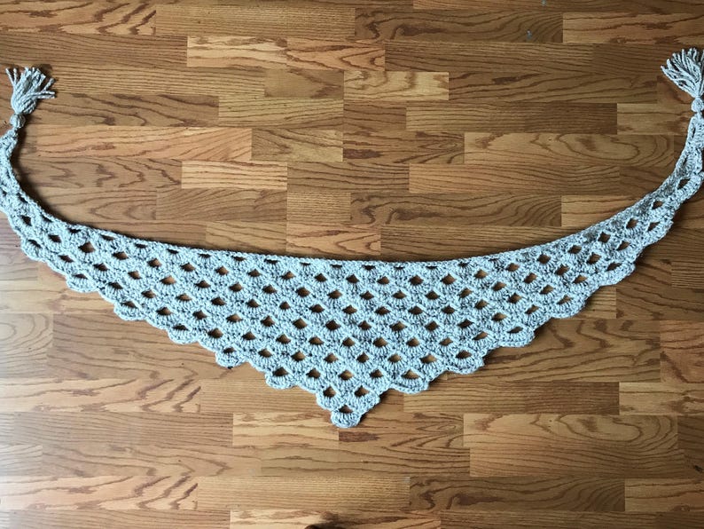 Peut inclure: Une &eacute;charpe en crochet gris clair avec un motif en losange et des glands frang&eacute;s &agrave; chaque extr&eacute;mit&eacute;.