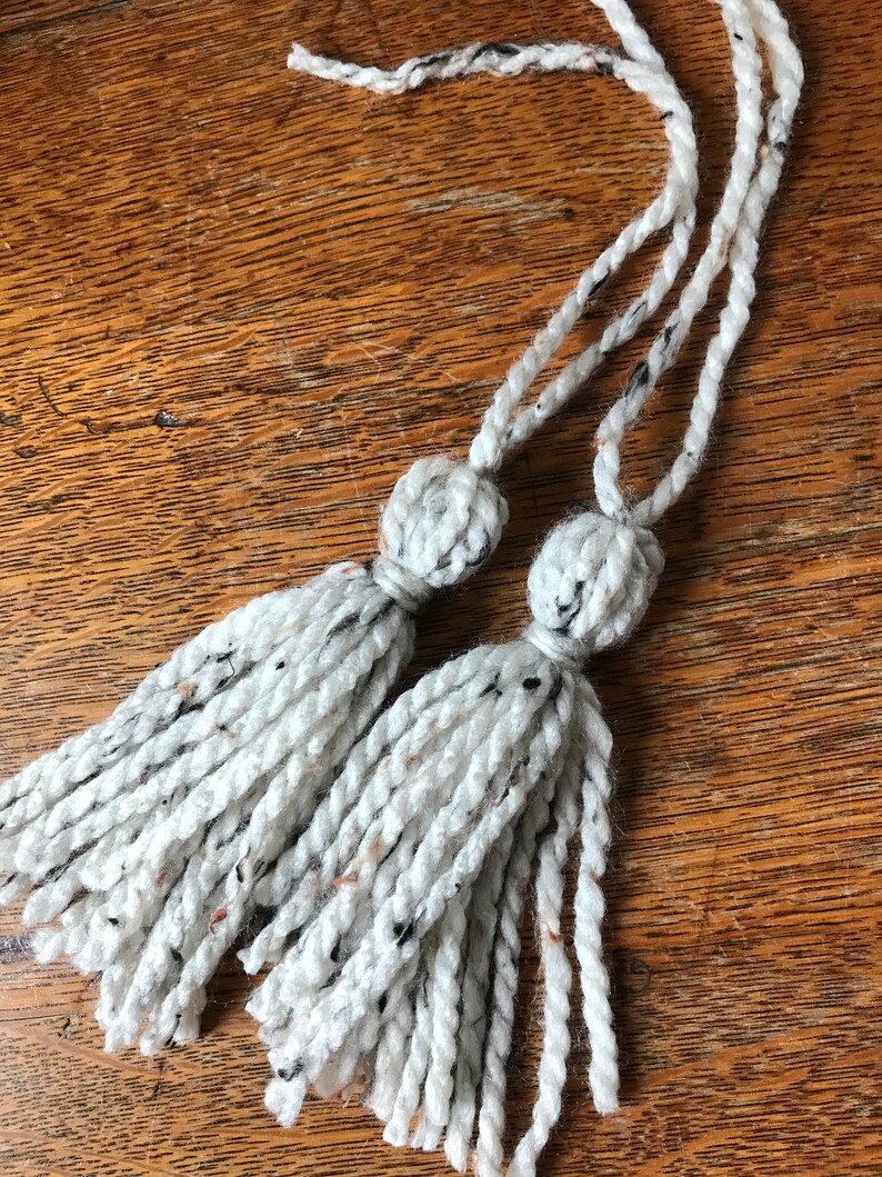 Peut inclure: Deux glands en fil blanc et noir avec de longues cordes.