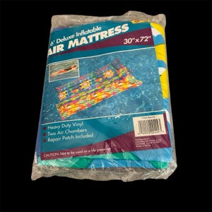 Op de afbeelding: Een verpakte 6' Deluxe opblaasbare luchtmatras, 76 cm x 183 cm, gemaakt van heavy-duty vinyl. De verpakking heeft een kleurrijk ontwerp met een afbeelding van de opgeblazen matras. Inclusief twee luchtkamers en een reparatiepatch. De verpakking is verzegeld in helder plastic.
