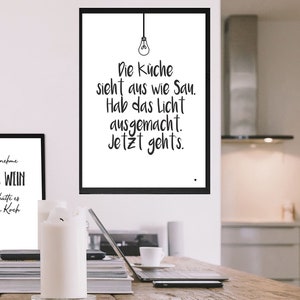 May include: Two black and white framed prints with German text. The top print says "Die K&uuml;che sieht aus wie Sau. Hab das Licht ausgemacht. Jetzt gehts." The bottom print says "Man nehme 1 Glas Wein und sch&uuml;tte es in den Koch."