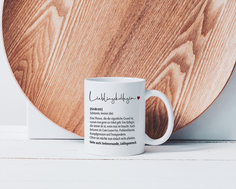 May include: White ceramic mug with a black and red design. The mug features the text "Lieblingskollegin" and a definition of the word "Sarah" in German.