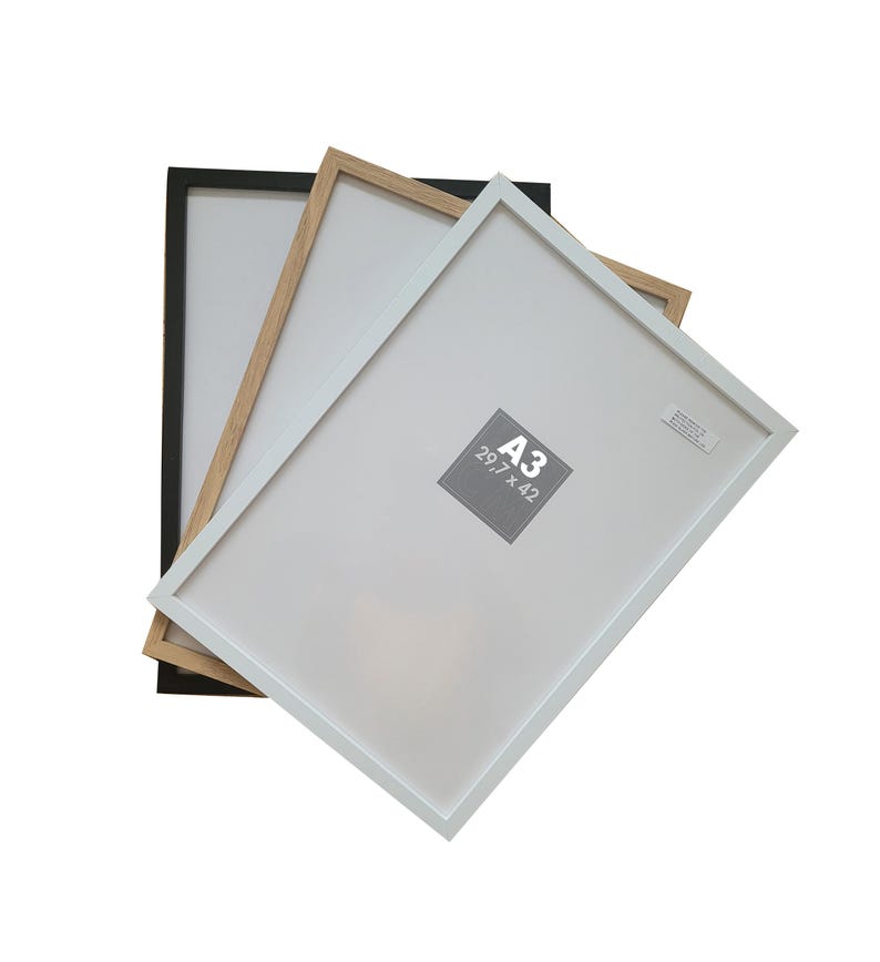 May include: Three picture frames in black, natural wood, and white. The frames are stacked on top of each other. The white frame is on top and has the size A3 (29.7 x 42 cm) printed on it.
