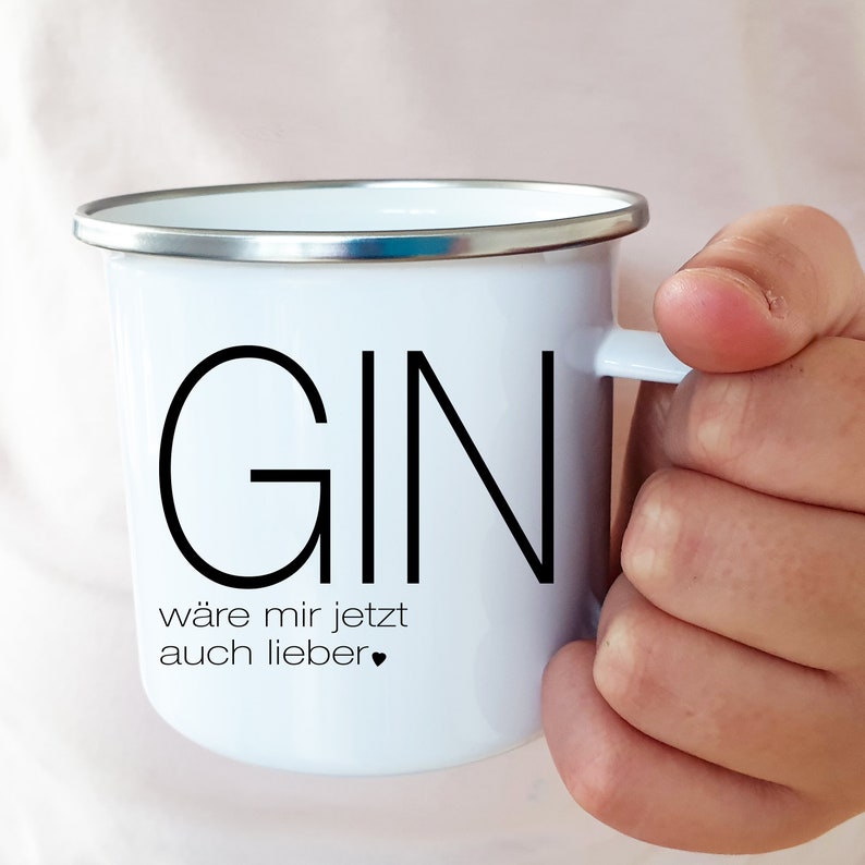 Puede incluir: Taza de esmalte blanco con un contorno negro de la palabra "GIN" y el texto "w&auml;re mir jetzt auch lieber" en negro.