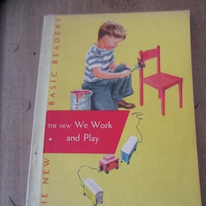 May include: A vintage children's book cover featuring a young boy painting a red chair with a paintbrush. The book title is "The New We Work and Play" and is part of the "Basic Readers" series.
