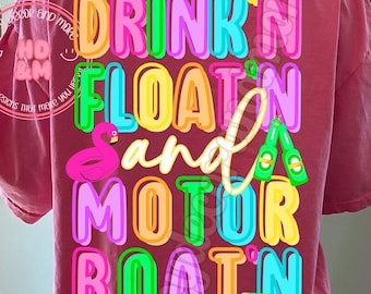 May include: A pink t-shirt with the text "DRINK'N FLOATIN and MOTOR BOATIN" in rainbow colors. The text is in a bubble font style. There is a pink flamingo float, a green and white motorboat, and a bottle of beer in the design.