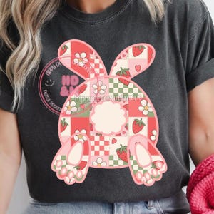 May include: A black t-shirt with a pink and red patchwork bunny design. The bunny has a checkered pattern and strawberries. The text "hippydecorandmore" is visible on the bunny.