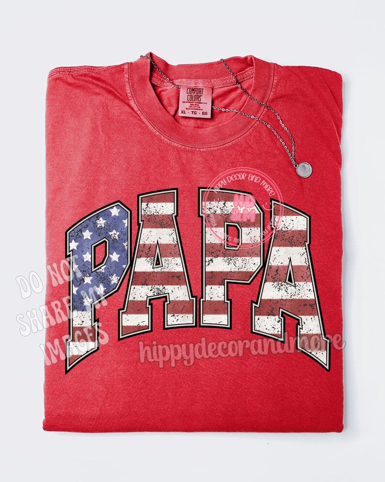 Puede incluir: Camiseta roja con un dise&ntilde;o de bandera estadounidense desgastado que deletrea "PAPA".