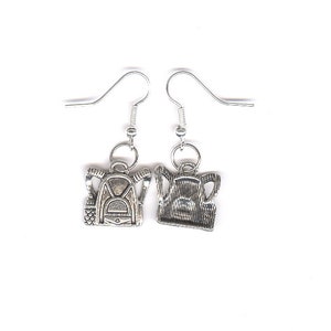 May include: A pair of silver earrings with backpack charms. The charms are detailed with zippers and straps.