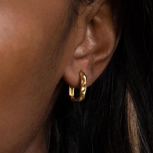 May include: A pair of gold hoop earrings with a textured finish. The earrings are small and delicate, and they are perfect for everyday wear.