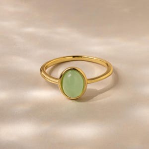 May include: A gold ring with a light green oval gemstone.