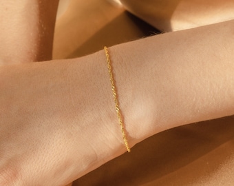 May include: A delicate gold chain bracelet with a twisted design.