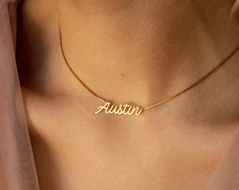 Peut inclure: Un collier doré composé d'une chaîne fine et d'un pendentif central en forme de plaque nominative portant le prénom Austin écrit en lettres cursives. Le métal présente une finition polie qui reflète la lumière, offrant un aspect doré éclatant.