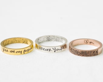 Könnte beinhalten: Drei Ringe aus Gold, Silber und Roségold mit gravierten Botschaften. Der goldene Ring trägt die Inschrift "You are my purpose", der silberne Ring "Forever Yours" und der Ring aus Roségold ein Herz und das Wort "You".