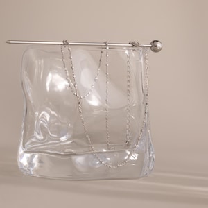 Close-up of the Dot Station Necklace in silver displayed on a clear glass, featuring a dainty beaded chain design.
