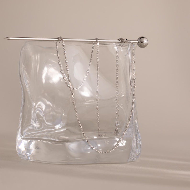 Close-up of the Dot Station Necklace in silver displayed on a clear glass, featuring a dainty beaded chain design.