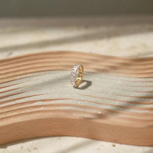May include: A gold ring with a row of clear rectangular stones set in a band.