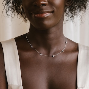 May include: A silver chain necklace with small, sparkling star-shaped charms.