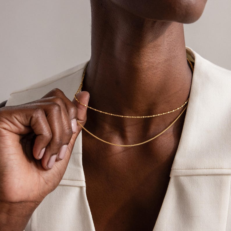 Model wearing the Dot Station Necklace in gold, featuring a dainty beaded chain design, layered with a matching gold chain necklace.