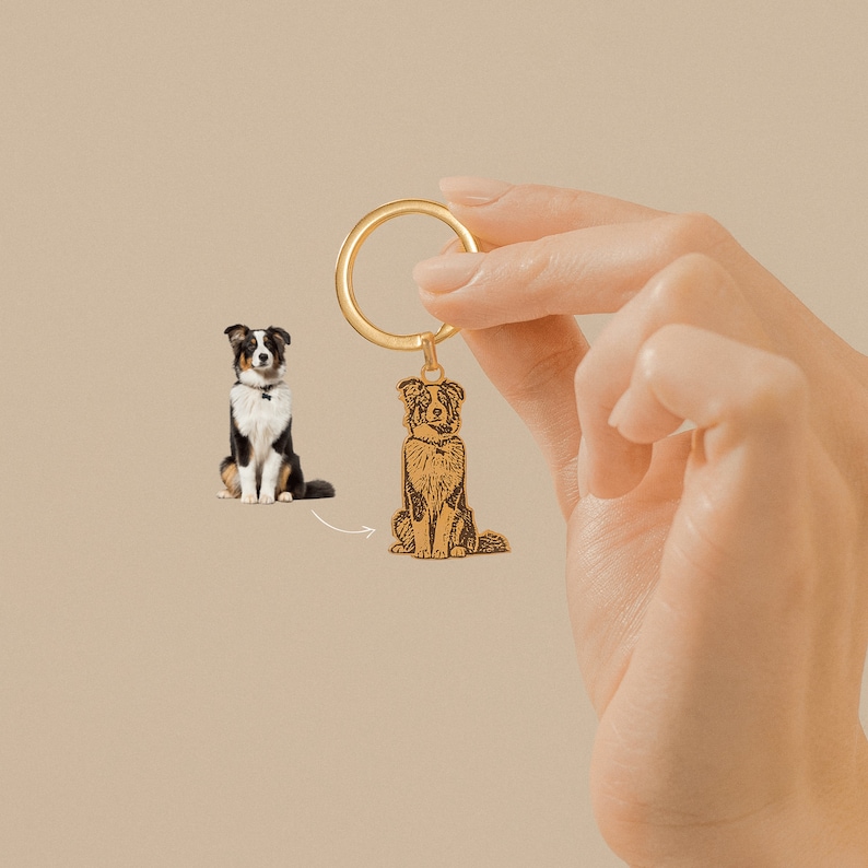 May include: Gold-toned metal keychain with a laser-engraved image of a black and white dog sitting. The keychain is attached to a gold-toned metal ring.