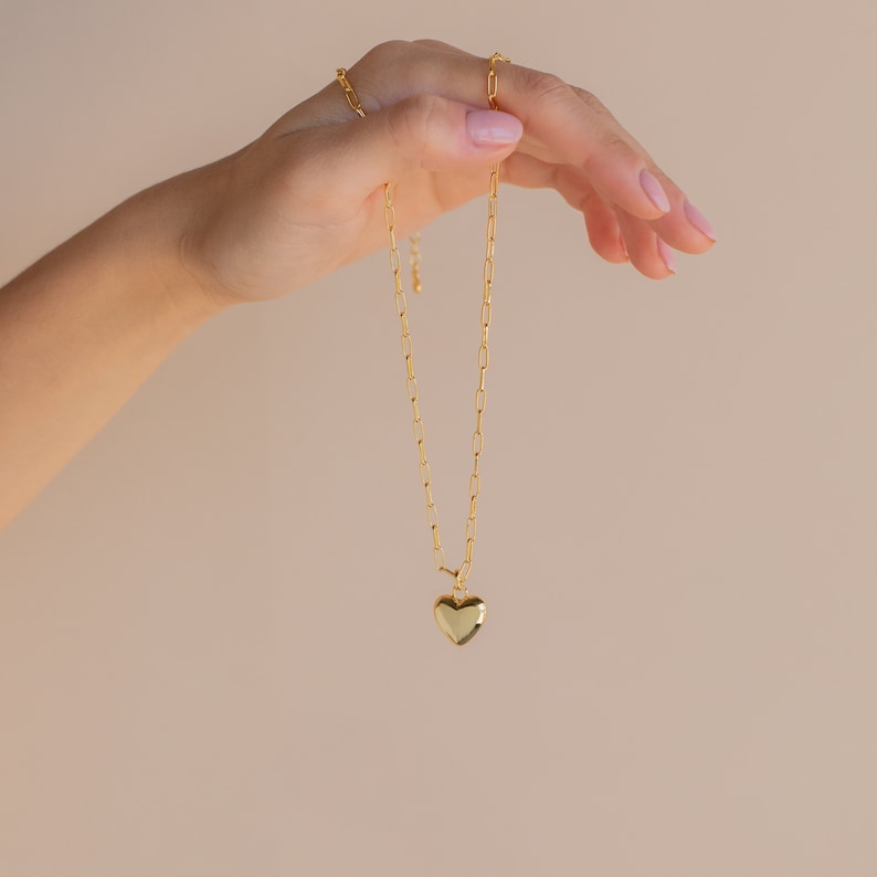 May include: A gold chain necklace with a heart-shaped pendant.