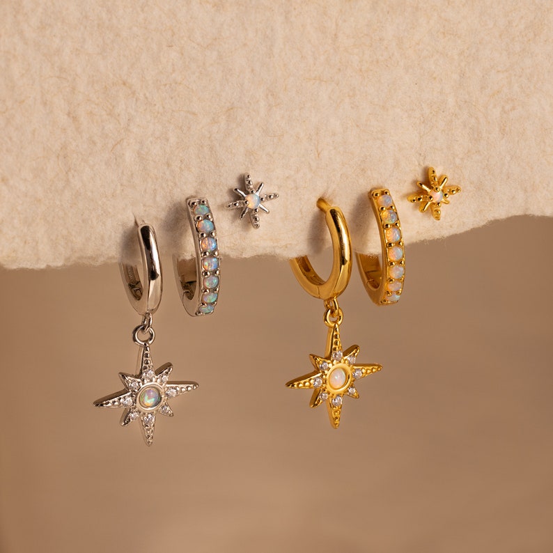 May include: A set of three pairs of earrings featuring a starburst design with opal accents. The earrings are available in both gold and silver.