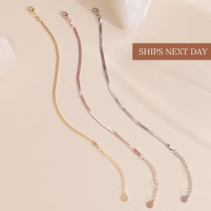 May include: Four delicate chain necklaces in gold, rose gold, and silver tones. Each necklace features a thin, flat snake chain design with a lobster clasp closure and an adjustable chain. The image includes the text "SHIPS NEXT DAY".