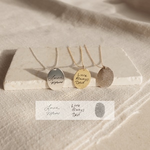 May include: Three silver necklaces with oval pendants. The pendants feature handwritten text, "Love Mom", "Love Always Dad", and a fingerprint design.