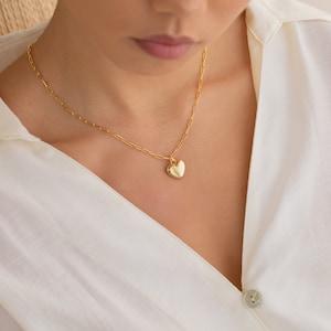 May include: A gold chain necklace with a heart-shaped pendant.
