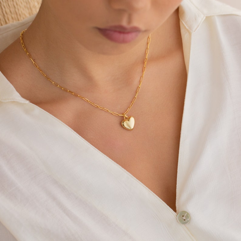 May include: A gold chain necklace with a heart-shaped pendant.
