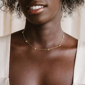 May include: A gold necklace with a delicate chain and small star-shaped charms.