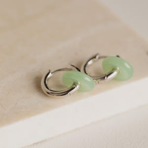Peut inclure: Une paire de cr&eacute;oles argent&eacute;es avec un accent en jade vert clair. Les boucles d'oreilles sont simples et &eacute;l&eacute;gantes.