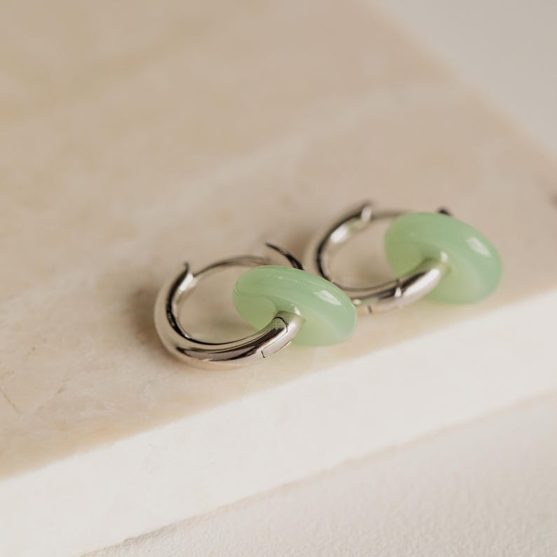 Peut inclure: Une paire de cr&eacute;oles argent&eacute;es avec un accent en jade vert clair. Les boucles d'oreilles sont simples et &eacute;l&eacute;gantes.