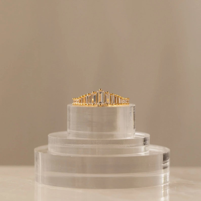 May include: A gold ring with a row of clear baguette-shaped stones set in a delicate, curved design.