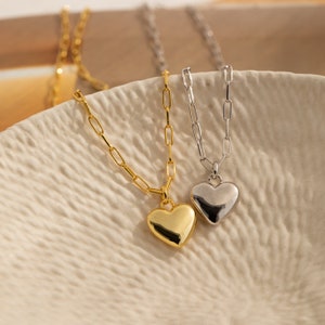 May include: Two gold and silver necklaces with heart pendants. The gold necklace has a larger heart pendant than the silver necklace.