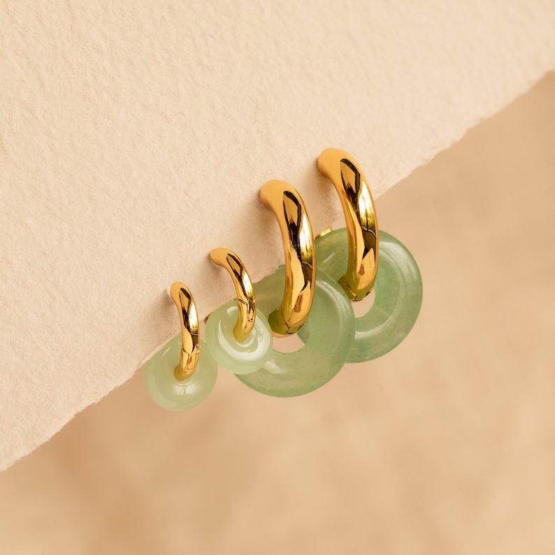 Peut inclure: Ensemble de quatre boucles d'oreilles cr&eacute;oles dor&eacute;es avec des accents de jade vert. Les cr&eacute;oles sont gradu&eacute;es en taille, la plus grande en haut et la plus petite en bas.