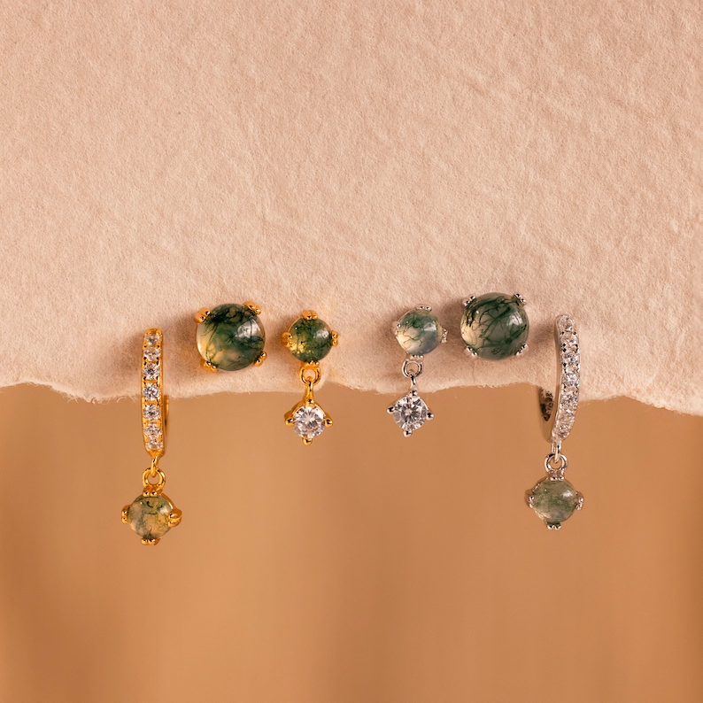 May include: Three pairs of earrings with green agate stones and clear cubic zirconia accents. The earrings are in gold and silver.