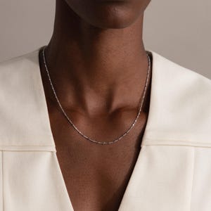 Model wearing the Dot Station Necklace in silver, featuring a dainty beaded chain design.