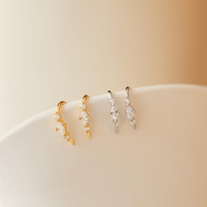 Könnte beinhalten: Ein Set aus drei Keramikbechern mit gesprenkelter, matter Oberfläche. Die Becher sind in Creme-, Hellgrau- und Dunkelgrautönen gehalten. Jeder Becher hat ein schlichtes, minimalistisches Design.