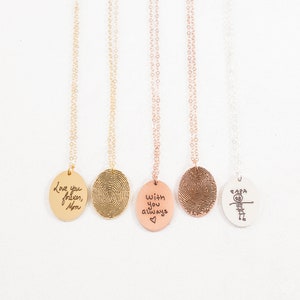 May include: Five gold, silver, and copper necklaces with oval pendants. The pendants feature fingerprint designs and personalized engravings. The engravings include "Love you forever, Mom", "With you always", and "Papa".
