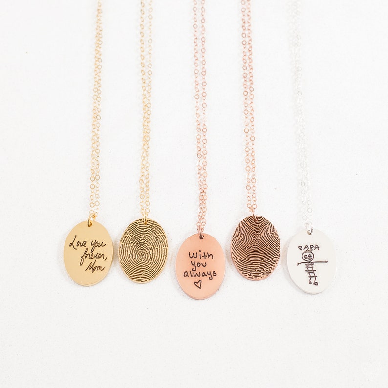 May include: Five gold, silver, and copper necklaces with oval pendants. The pendants feature fingerprint designs and personalized engravings. The engravings include "Love you forever, Mom", "With you always", and "Papa".