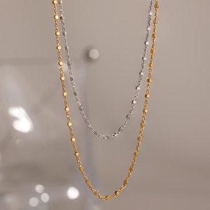 Close-up of two Dot Station Necklaces in silver and gold, each featuring a dainty beaded chain design.