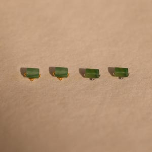 K&ouml;nnte beinhalten: Vier gr&uuml;ne Jade-Ohrringe mit goldenen und silbernen Verschl&uuml;ssen. Die Ohrringe sind rechteckig und haben eine hellgr&uuml;ne Farbe.