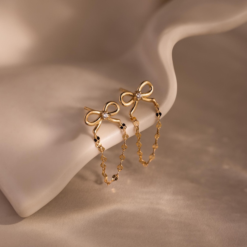 Bow Chain Studs featuring delicate chain details, showcased on a curved cream surface—ideal for those who love feminine and vintage-inspired jewelry styles.