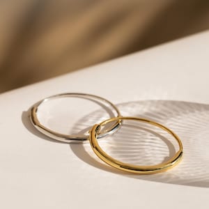 Peut inclure: Deux boucles d'oreilles créoles circulaires, l'une avec une finition argentée polie et l'autre avec une finition dorée polie. Chaque boucle présente un anneau métallique lisse et continu avec un mécanisme de fermeture à charnière simple.