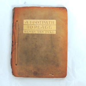 Könnte beinhalten: Ein Vintage-Buch mit dem Titel "A Footpath to Peace" von Henry Van Dyke. Der Einband hat eine abgenutzte, bräunlich-orange Farbe, mit dem Titel und dem Namen des Autors in einer helleren, geprägten Schrift. Das Buch ist mit einer einfachen Schnur gebunden.