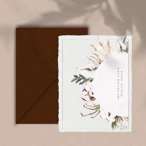 May include: A white invitation card with a watercolor floral design featuring cotton, leaves, and a circular space for text. The text "Invitation Card Design Ideas" is printed on the right side of the card.